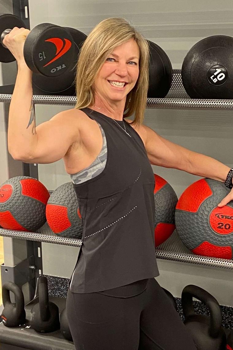 Michelle Lobdell flexing beside the medicine ball rack at the studio